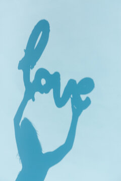 Shadow of a woman holding a balloon with the word "love".