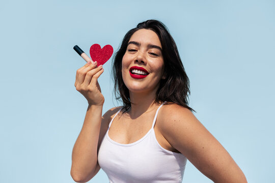 Young woman holding a heart and a beauty product