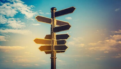 Blank directional road signs against blue sky. Black metal arrows on the signpost. Warm toned colors. Old style image