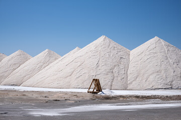 The brilliant white of salt mountains stands out in the bright sunlight, with a lone wooden...