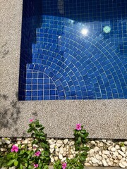 edge of feet in bright blue round tile design in pool - travel texture in Cambodia