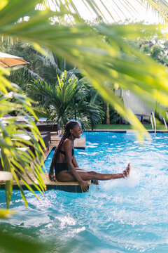 Cheerful young black woman relaxing on poolside in hotel
