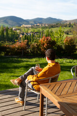 Man sitting on his garden terrace with a glass of wine admiring the scenery of mountains. concept...