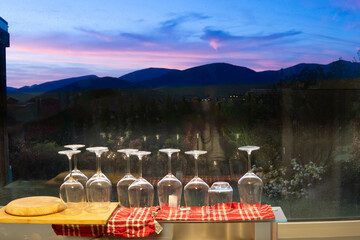 photograph from a window with wine glasses drying and landscape views of mountains dusk in pink...