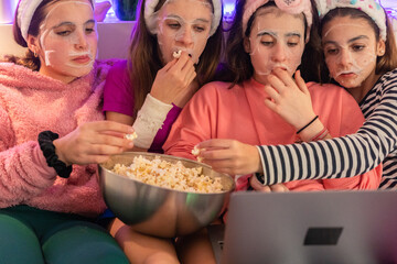 Young girls with facial mask watching movie in laptop