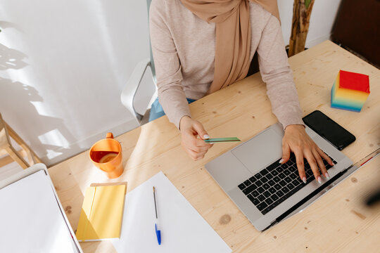 Crop woman in hijab making online credit card payment