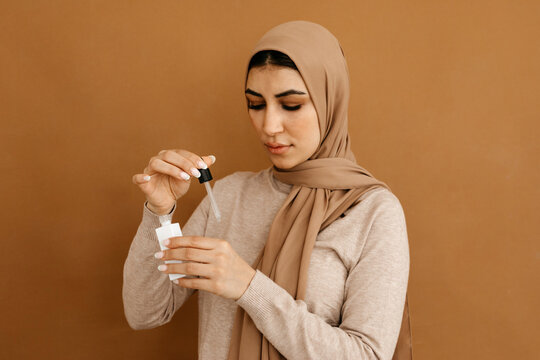 Muslim woman applying serum on hand in studio