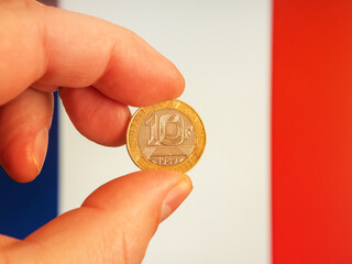 French 10 Franc Coin 1989 Held in Hand Against France Flag Background