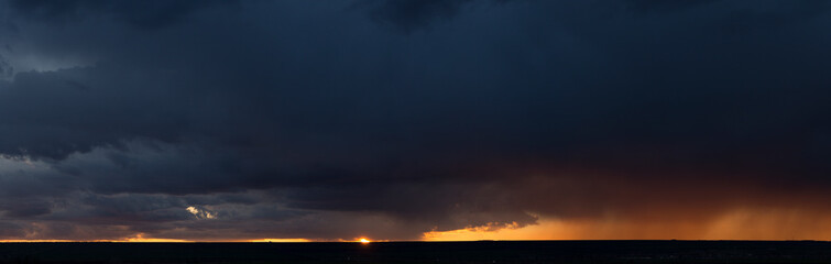 Naklejka na ściany i meble Landscape at sunset. A thunderstorm is approaching the village. Tragic gloomy sky. Panorama.