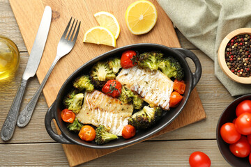 Tasty cod cooked with vegetables served on wooden table, flat lay