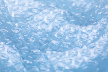 Transparent bubble wrap on light blue background, closeup