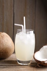 Glass of coconut water, ice cubes and nuts on wooden table - obrazy, fototapety, plakaty
