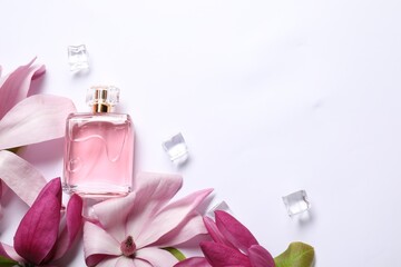Beautiful pink magnolia flowers, bottle of perfume and ice cubes on white background, flat lay....