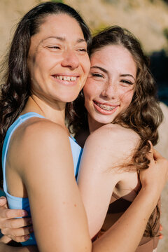 Happy mother and her teenage smiling daughter embracing each other