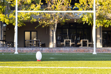 A rugby ball resting on tee, ready for a kick-off on field outdoors, copy space