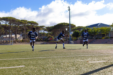 Three African American young male athletes training on a sunny field