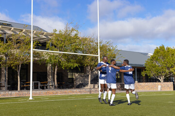 Three African American young male athletes celebrating on a rugby field outdoors