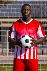 African American young male athlete holding a soccer ball on field outdoors