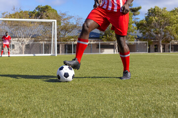 Two African American young male athletes are playing soccer on field outdoors