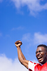 African American athlete celebrating against blue sky, copy space
