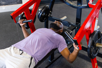 African American young male athlete lifting weights in gym