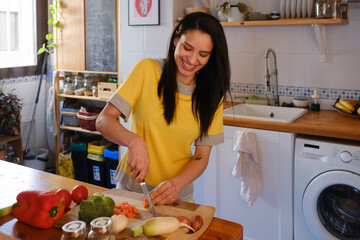 happy Woman in the kitchen cutting vegetables on chopping board