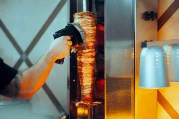 Rotisserie Fast Food Worker Using a Cordless Meat Slicer Machine. Chef working in a professional...