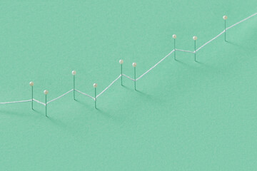 White string connecting push pins representing growing financial chart