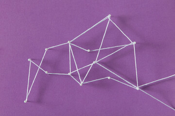 Top view of stationery straight pins connected with white thread