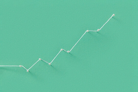 Stationery pins tied with white string on green paper background