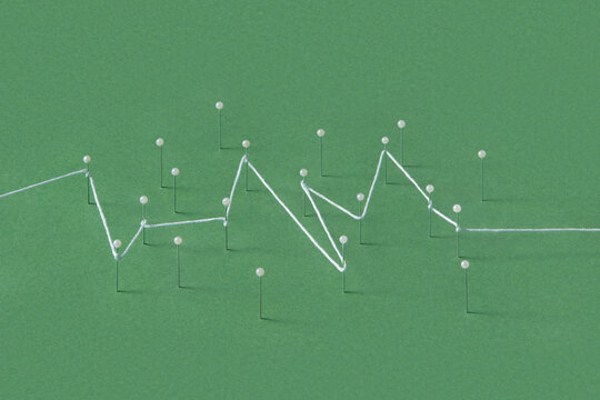 Straight push pins stuck in green paper sheet and tied with string