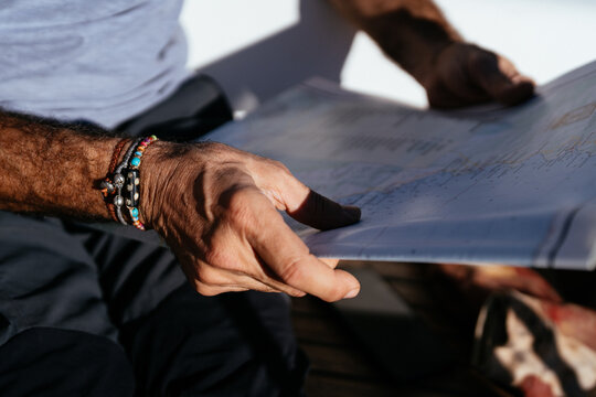 Unrecognizable stylish man in trousers reading map