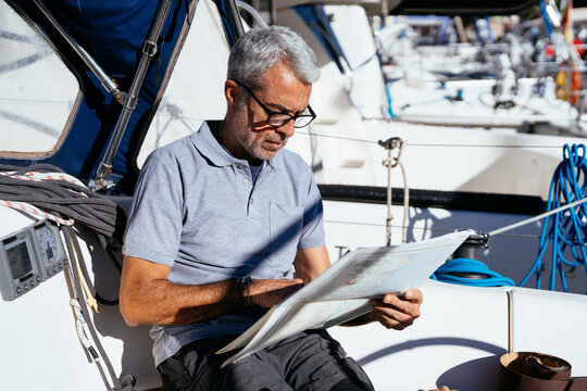 Concentrated senior man on yacht reading map