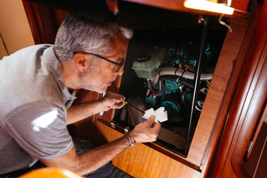 Elderly male technician checking oil of yacht engine