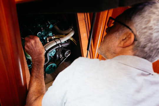 Senior mechanic fixing engine while working on yacht