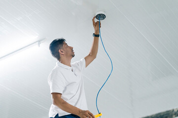 Focused engineer pulling wire installing security camera equipment