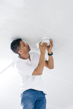 Man employee installing security camera in room