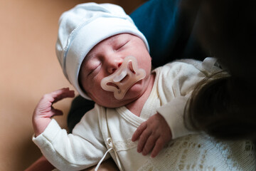 Little baby wearing hat and with pacifier in mouth