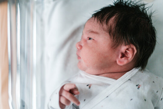 Cute newborn child lying in baby cot in hospital room