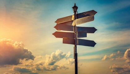 Blank directional road signs against blue sky. Black metal arrows on the signpost. Warm toned colors. Old style image