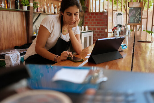 Bored Cashier at a restaurant on her phone