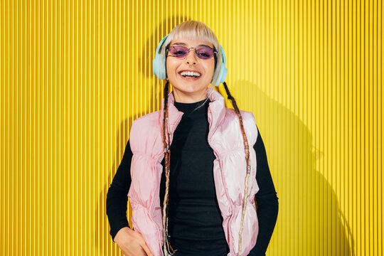 Fashionable alternative woman with headphones over yellow background