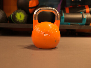 This is an orange kettlebell photographed at a gym.