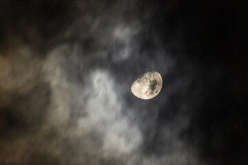 Full moon in the night sky with dark clouds, closeup of photo
