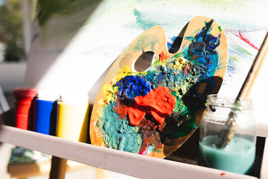 A palette covered in colorful paint rests on an easel at home