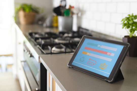 A tablet displaying colorful graphs of smart home app energy usage sits on kitchen counter