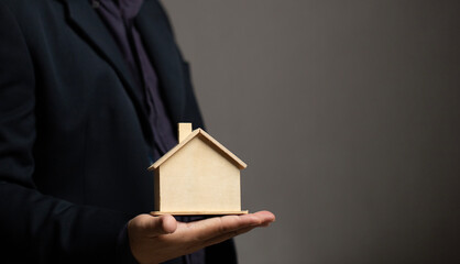 Businessman Hand holding model house for buy real estate concept. For investment property estate for family. Insurance plan. Mortgage finance loan.