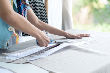 Close up, hand of dressmaker or fashion designer working in her workshop, use fabric scissors for...