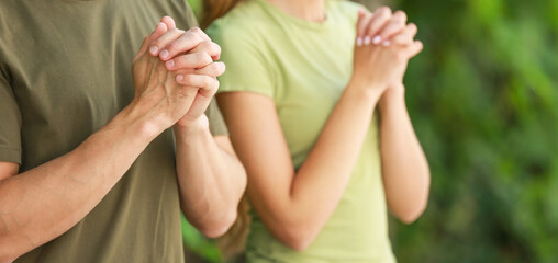 Religious couple praying to God outdoors