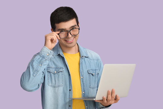Male programmer with laptop on lilac background